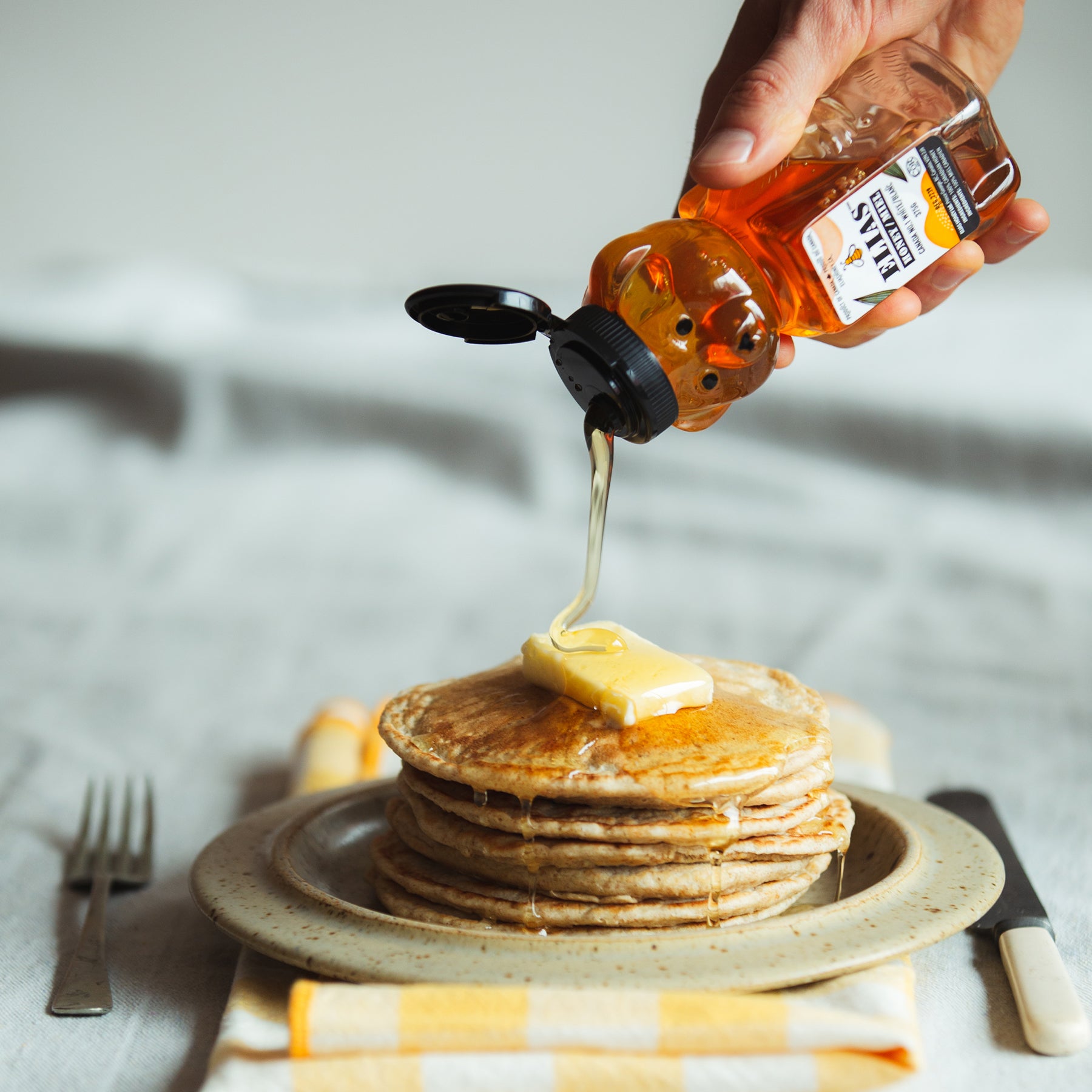 Image of Elias Honeybear pure liquid honey being poured onto pancakes.