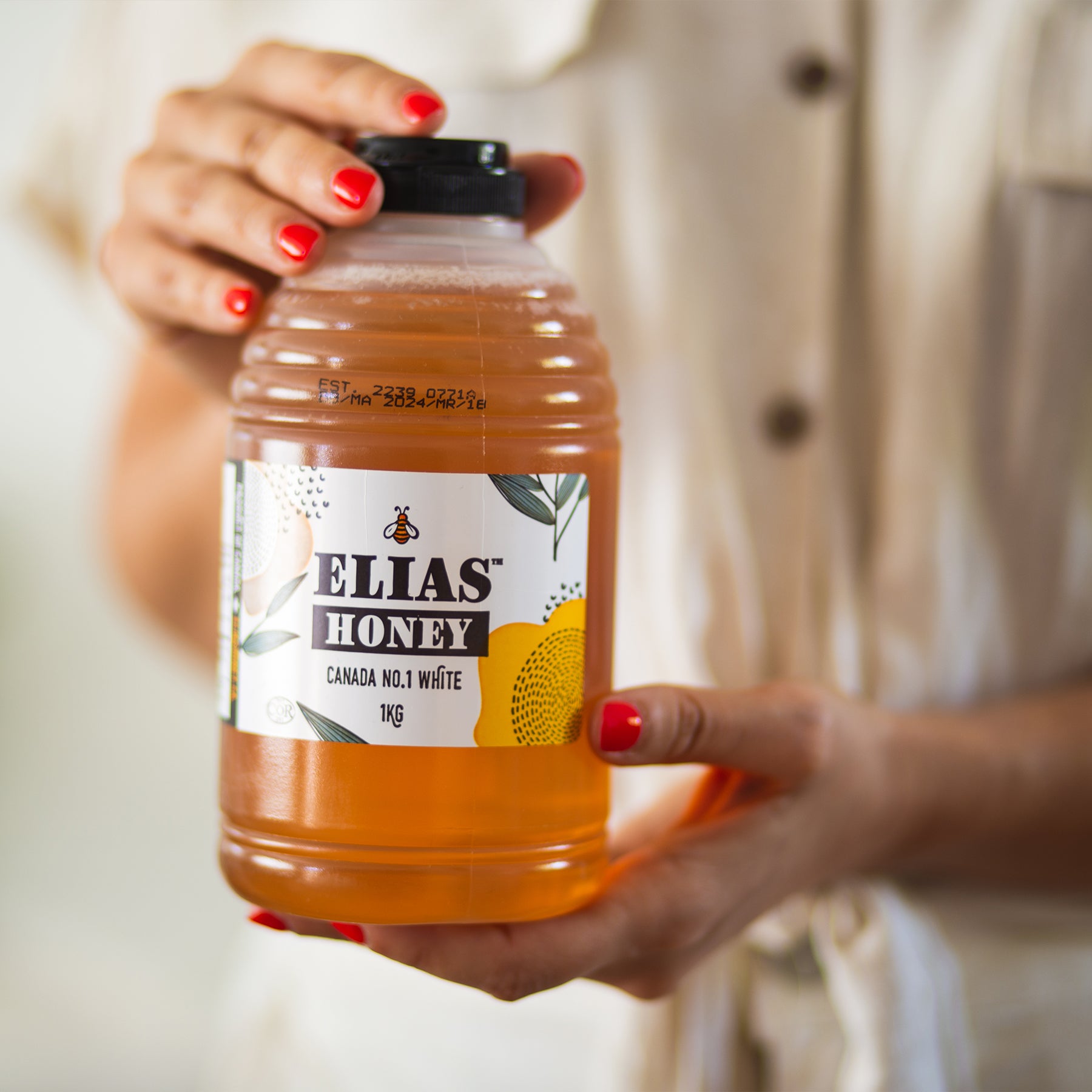 Image of woman holding a bottle of Elias Honey Pure Liquid Honey 