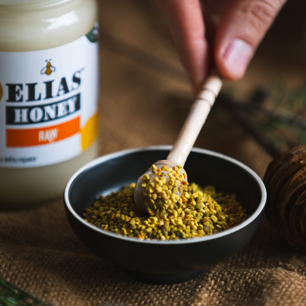 Image of Elias Raw Honey with honey stick in Elias pure bee pollen.